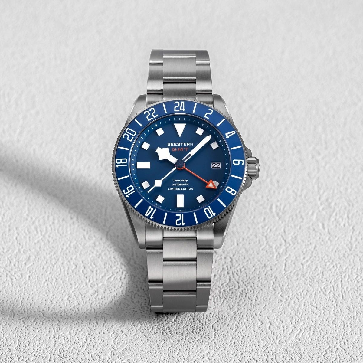 Seestern S462 titanium GMT, blue dial, front flat-lay on white textured surface, steel bracelet