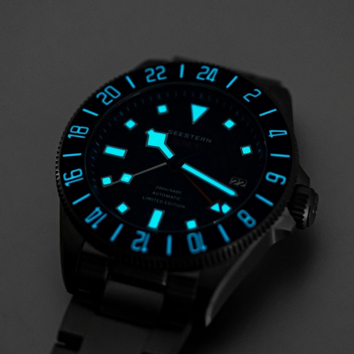 Seestern S462 titanium GMT blue dial and bezel glowing blue lume in the dark, angled close-up