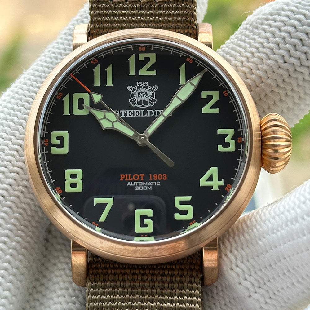 Steeldive SD1903S bronze pilot watch dial close-up with green numerals, minute track and date window at 6