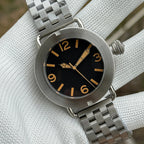 Steeldive SD1912 dial macro showing black face, faux-patina Arabic numerals and aged syringe hands at 47mm