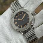 Steeldive SD1912 black dial macro with orange Arabic numerals, gold spear hands and shark mesh bracelet