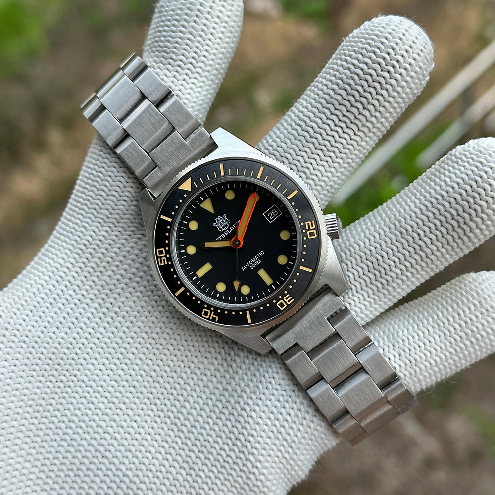 STEELDIVE SD1929V on a steel bracelet held in a gloved hand, black dial with orange minute hand