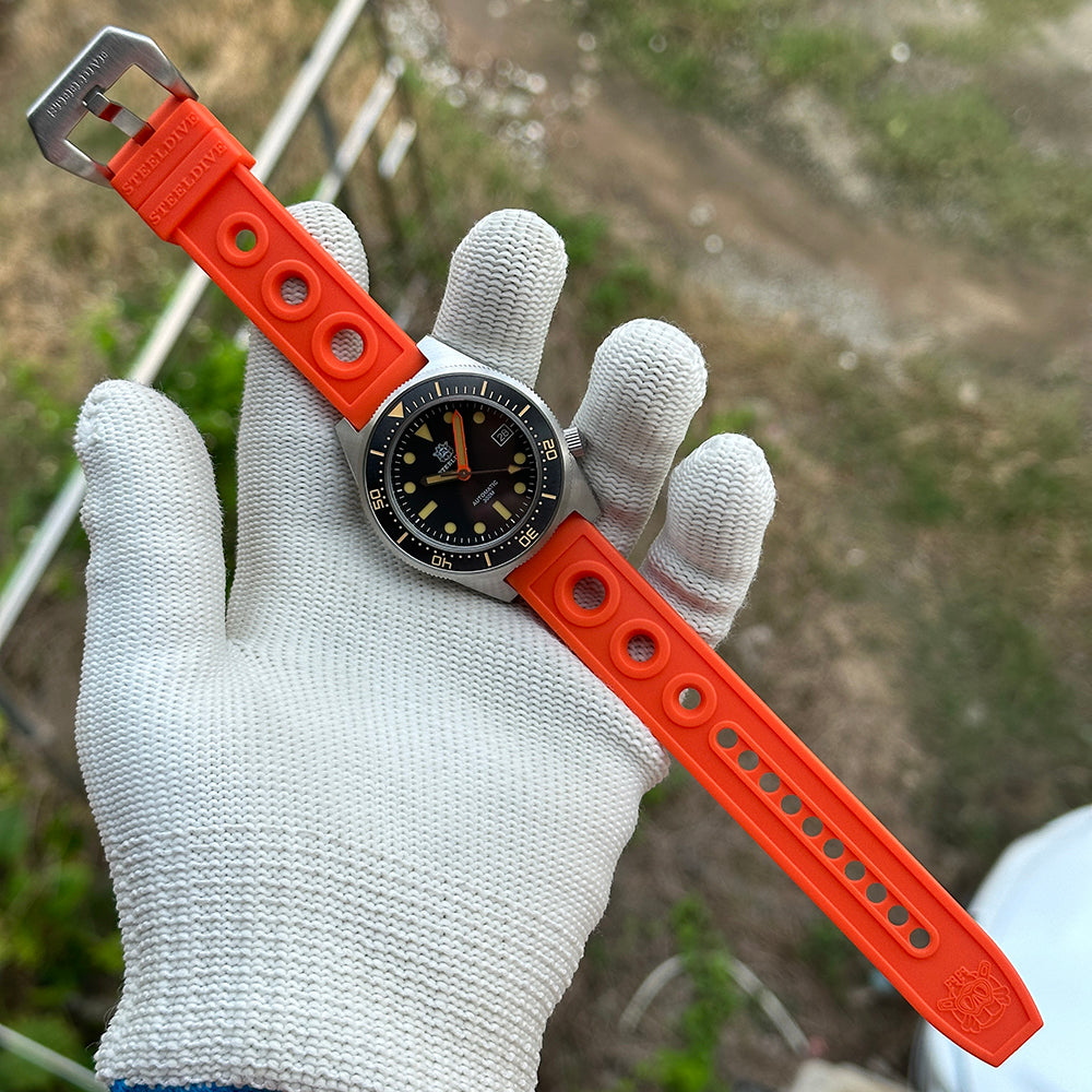 STEELDIVE SD1929V on its orange perforated rubber strap held in a gloved hand