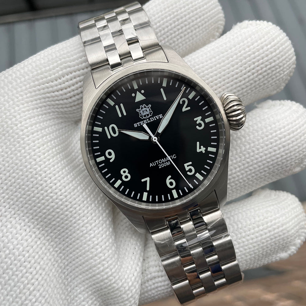 Steeldive SD1930 pilot watch black dial three-quarter angle on stainless steel bracelet, gloved hand