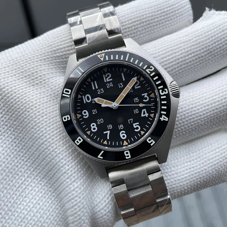 Steeldive SD1944 automatic diver watch with black dial, orange and white accents, black bezel, and silver stainless steel bracelet, displayed on a white textured background.