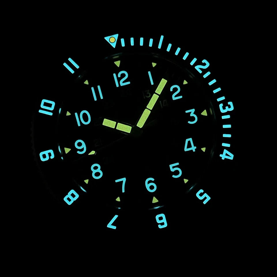 Steeldive SD1944 luminous diver watch dial glowing blue numerals and green hands in the dark against a black background, with orange triangle at 12 o'clock and luminous bezel.