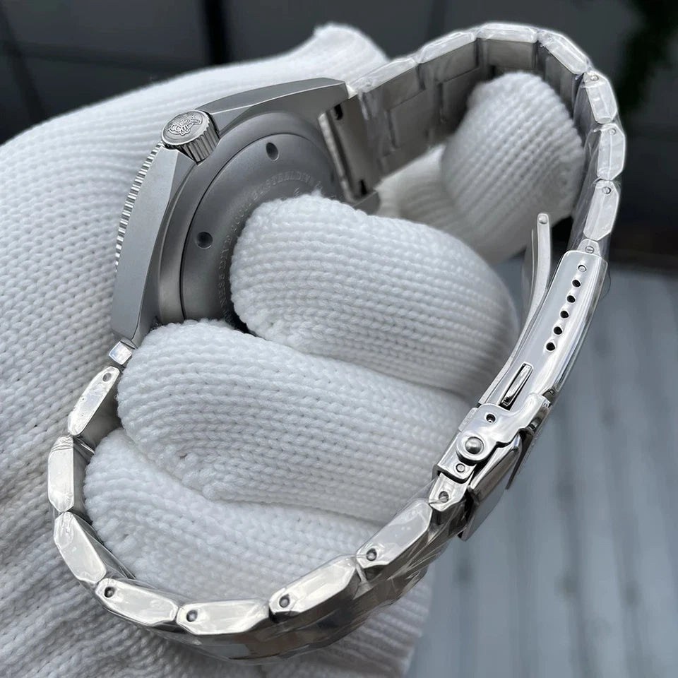 Side view of Steeldive SD1944 watch with stainless steel case and bracelet, crown visible, held by white gloved hand with blurred background.
