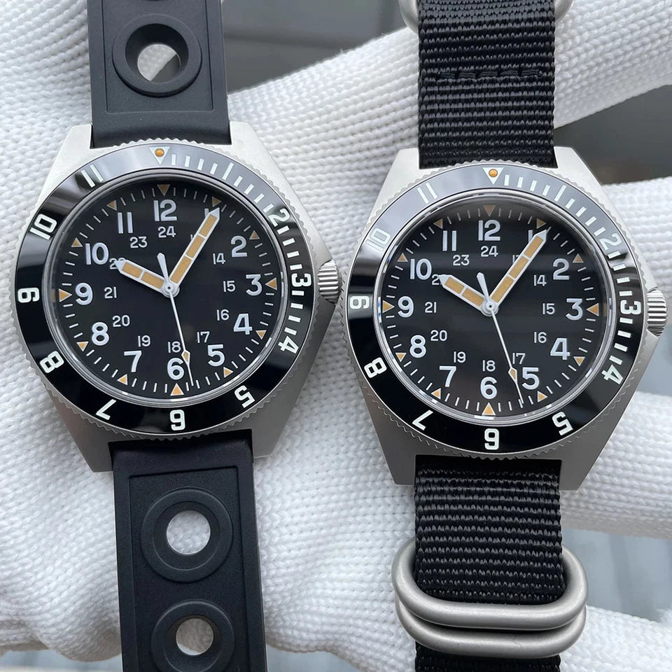 Steeldive SD1944 watches side by side: left watch with black rubber strap, right watch with black nylon strap with steel loops, both with black dials and orange triangle markers, on white cloth background.