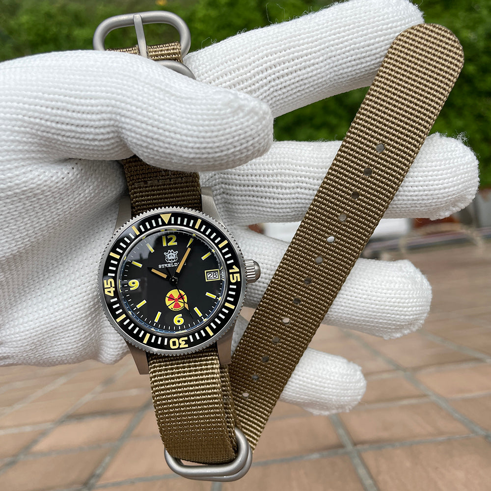 Steeldive SD1952T watch on khaki NATO strap held in gloved hand outdoors