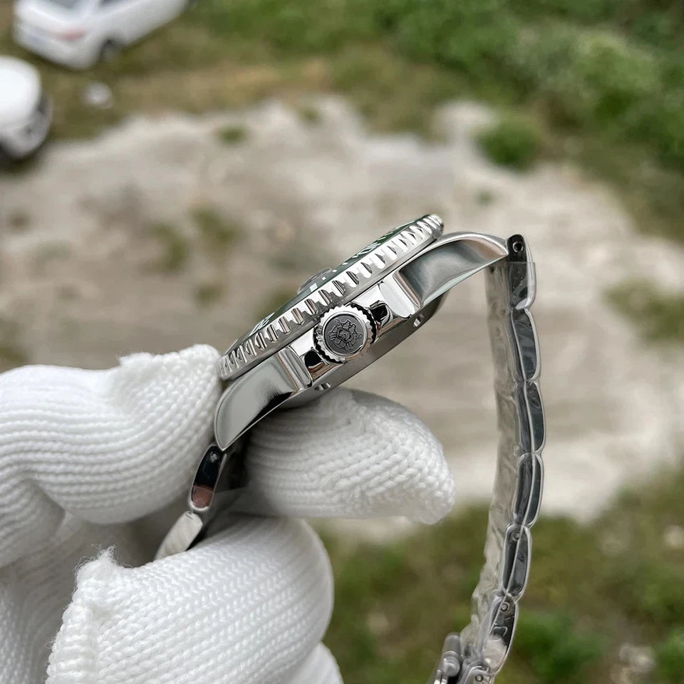 Side view of Steeldive SD1953 automatic diver watch case and silver stainless steel bracelet held by a gloved hand against blurred natural background.