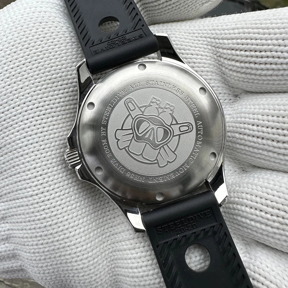 Back view of Steeldive SD1957 watch showing engraved diver logo on stainless steel case back with black rubber strap, placed on white gloved fabric background.