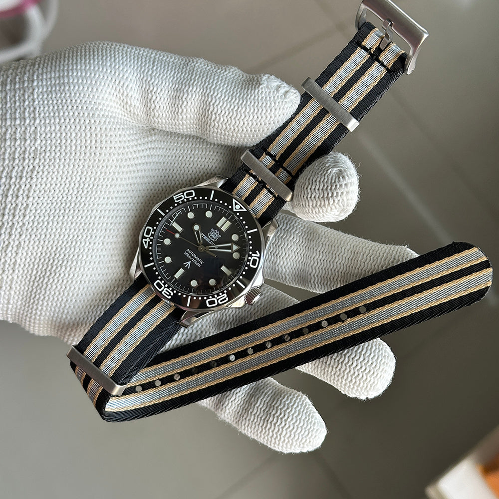 STEELDIVE SD1957L on a black, grey and sand striped nylon strap held in a gloved hand