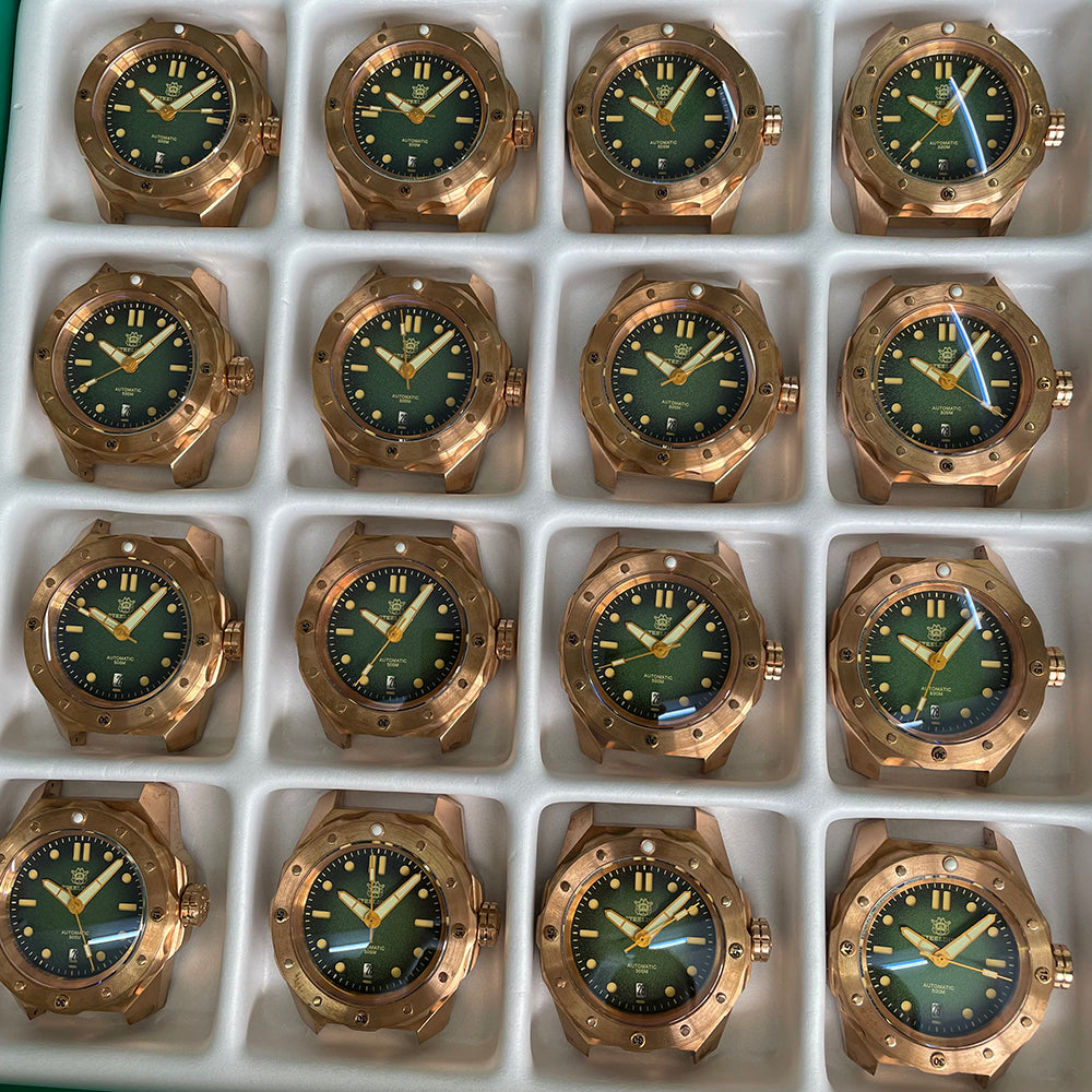 Steeldive SD1960S bronze green dial dive watch lineup in production tray showing patina variation