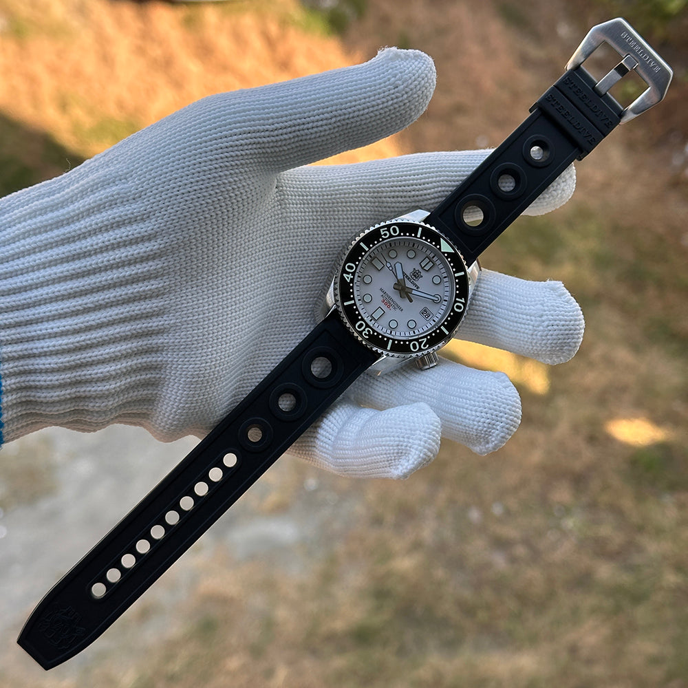 Steeldive SD1968 dive watch on hand showing black rubber strap and white dial, outdoor scene