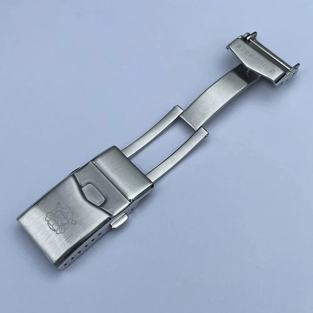 Steeldive SD1970C stainless steel deployment clasp and bracelet segment on light blue background with engraved logo.