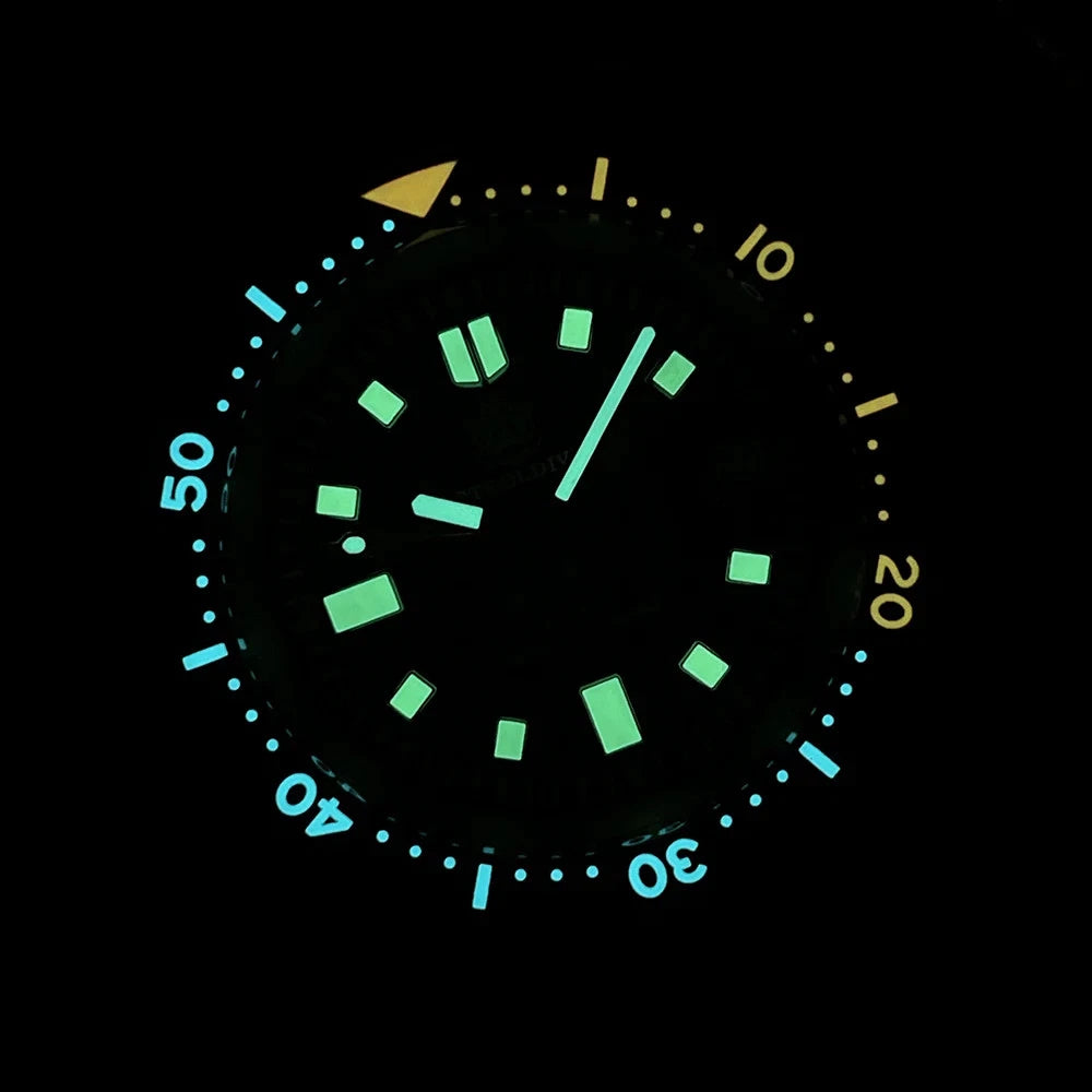Luminous dial of Steeldive SD1970C glowing green and blue on black background, showing minute markers and indices.
