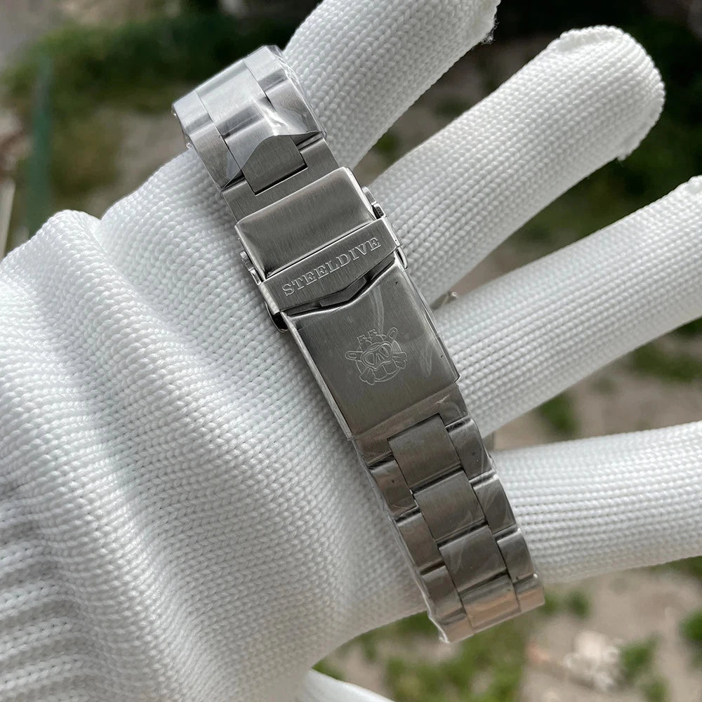 Steeldive SD1970C stainless steel bracelet with clasp engraved with Steeldive logo, held by gloved hand against natural background.