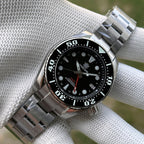 Steeldive SD1971GMT black bezel GMT watch on steel bracelet in gloved hand, wrist scene