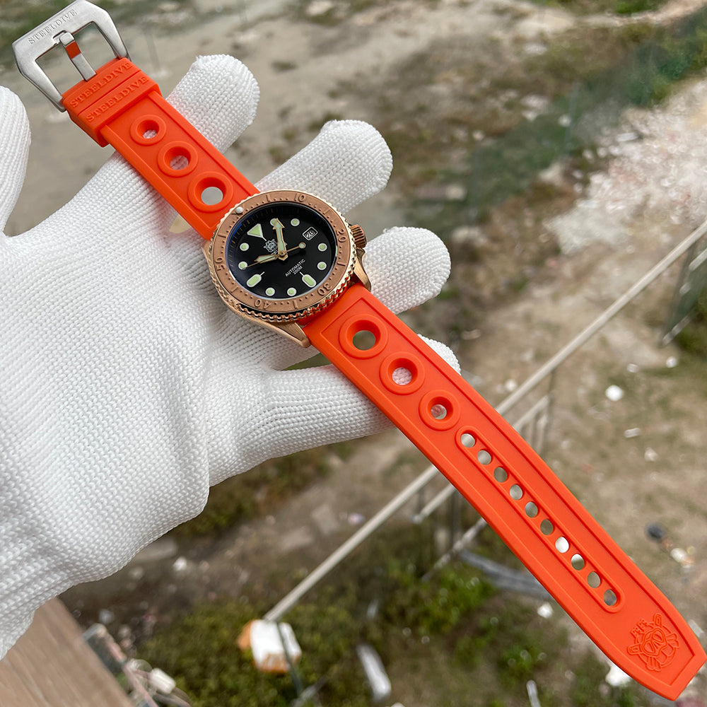 Steeldive SD1973S bronze watch laid out with full orange rubber dive strap and signed steel buckle