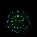 Steeldive SD1974 sapphire dive watch lume shot showing green hour markers and blue bezel pip in dark