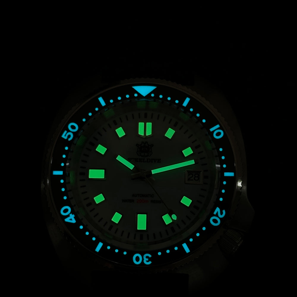 Steeldive SD1974 sapphire dive watch lume shot showing green hour markers and blue bezel pip in dark