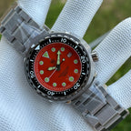 Steeldive SD1975 tuna dial macro showing matte orange face, applied lume dots and date window