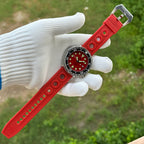 Steeldive SD1975 with red sunray dial and full red holed rubber strap laid out on gloved hand