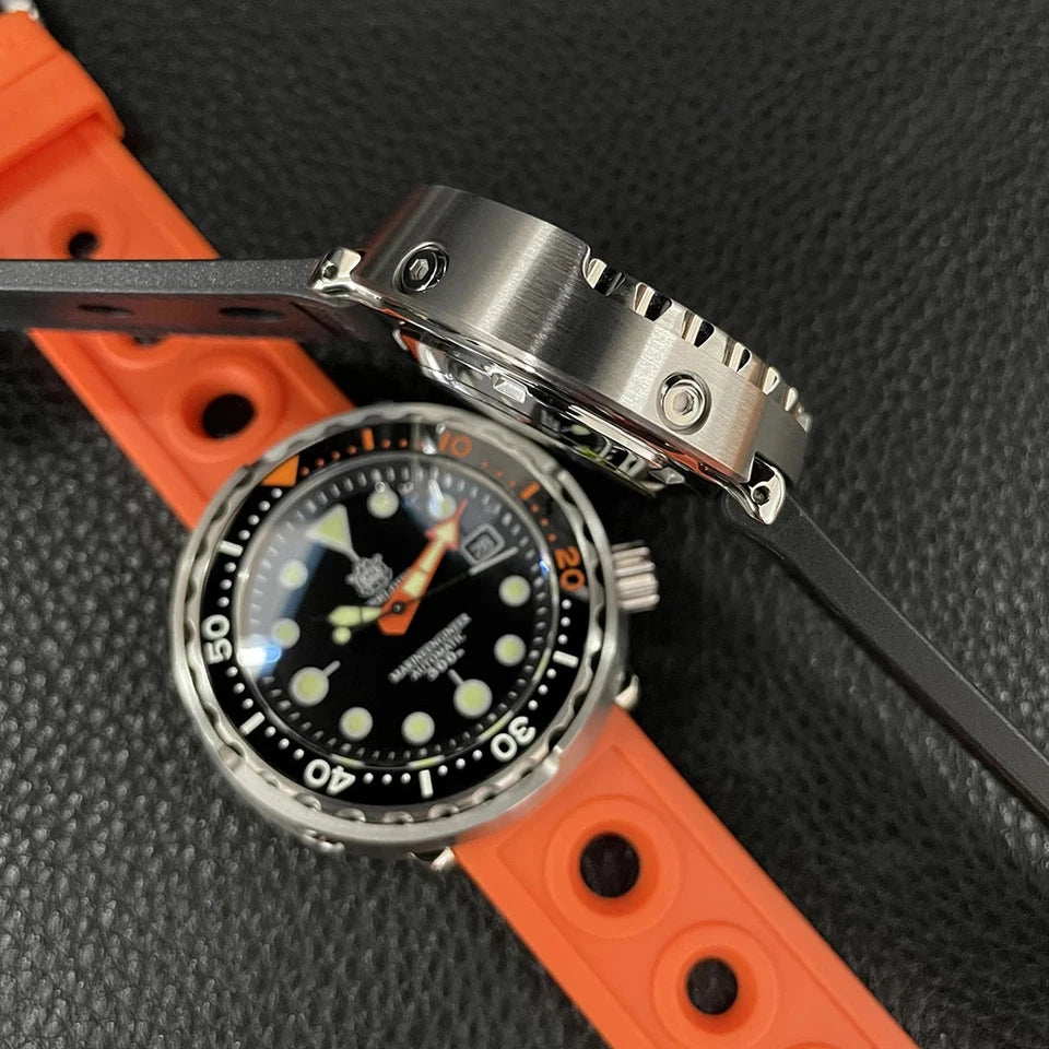 Side view of Steeldive SD1975C dive watch showing black dial with orange accents, stainless steel case, displayed with black strap across orange rubber strap, luminous markers and NH35 automatic movement.