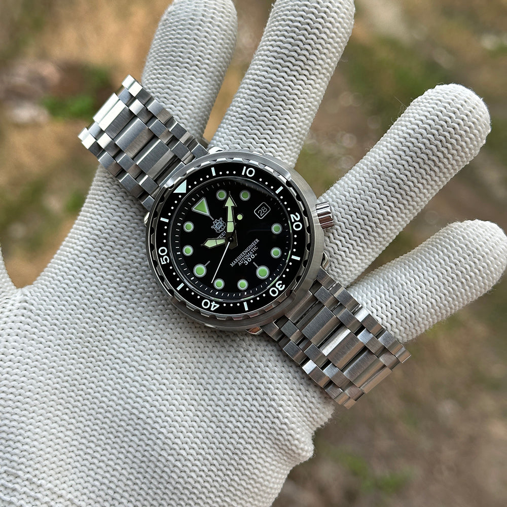 STEELDIVE SD1975K on a stainless steel tank bracelet held in a gloved hand