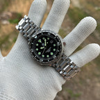 STEELDIVE SD1975K on a stainless steel tank bracelet held in a gloved hand