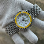 STEELDIVE SD1975N yellow bezel on a steel mesh bracelet held in a gloved hand