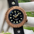 Steeldive SD1975S V2 bronze dive watch on woven backdrop with black rubber strap, lifestyle shot