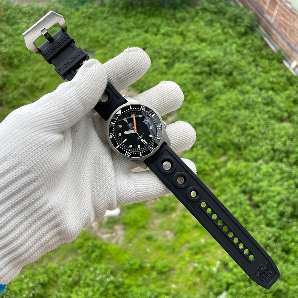 Steeldive SD1979 black dial held in gloved hand showing perforated black rubber strap
