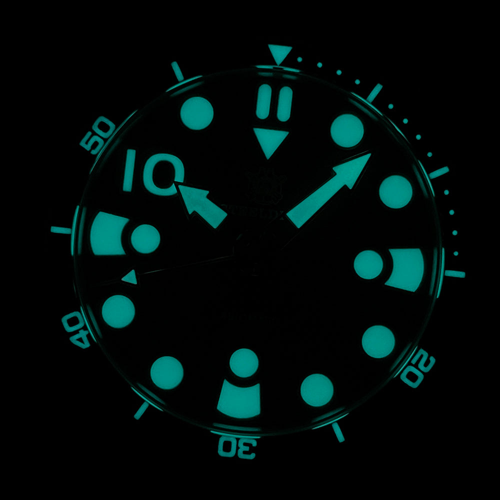 Steeldive SD1982 dial macro showing strong cyan blue lume on indices and hands in the dark
