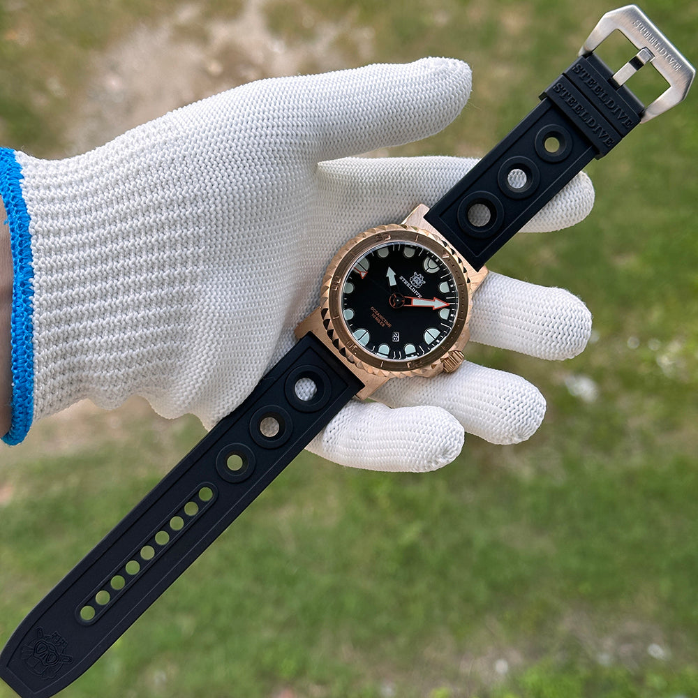 Steeldive SD1982S 46mm bronze dive watch with black rubber strap held in gloved hand outdoors