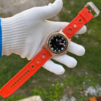 Steeldive SD1982S 46mm bronze dive watch with orange rubber strap held in gloved hand outdoors