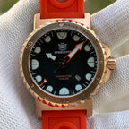 Steeldive SD1982S bronze dive watch wrapped in orange rubber strap, top-down detail in gloved hand