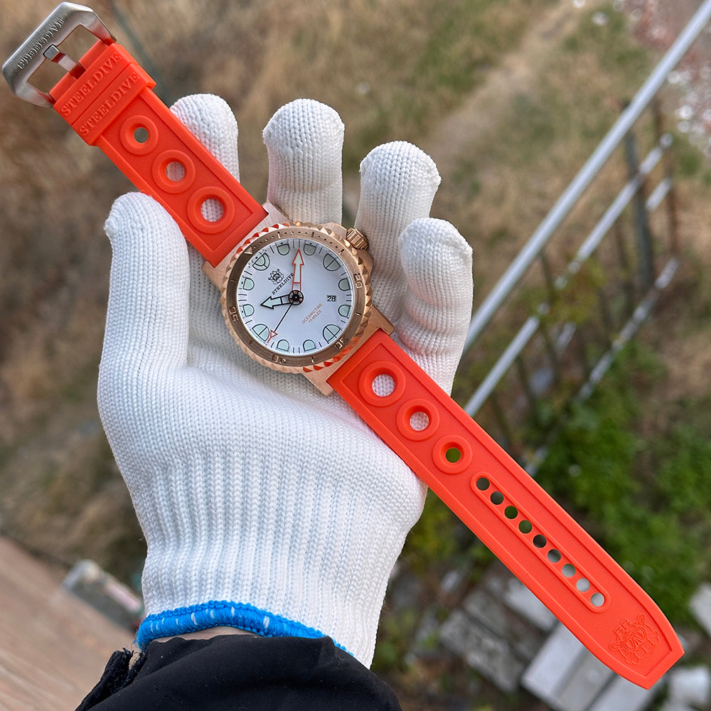Steeldive SD1982S bronze 56mm dive watch on gloved hand with orange rubber strap outdoors, wrist shot