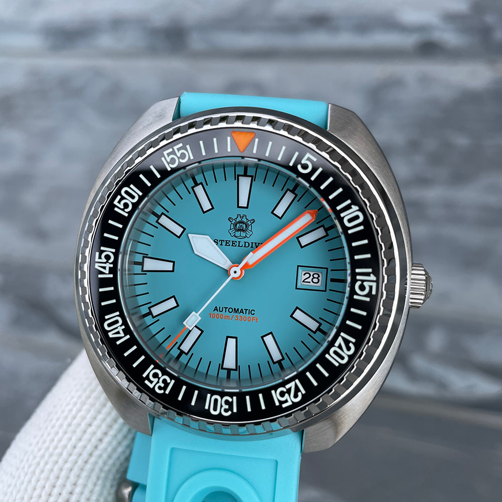 Steeldive SD1983 ceramic dive watch on cyan rubber strap, front dial view against gray stone backdrop