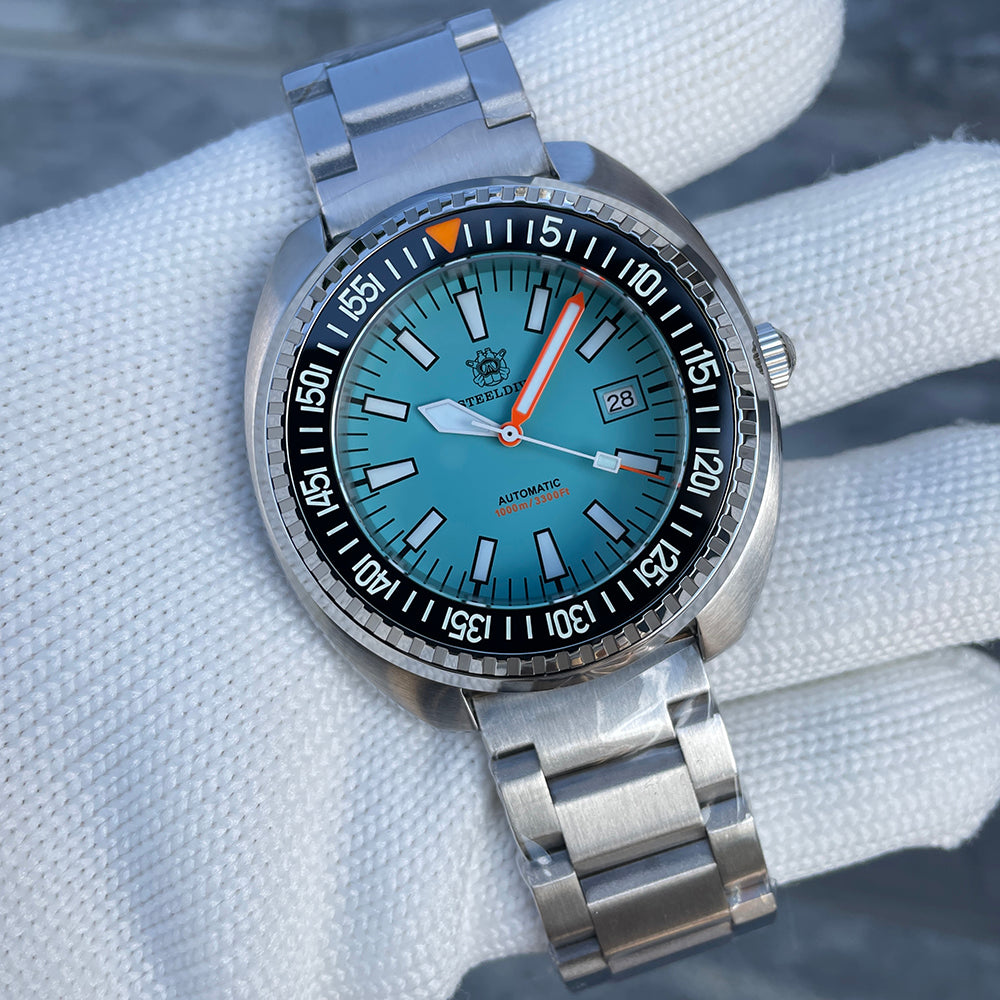 Steeldive SD1983 ceramic dive watch on oyster steel bracelet held in a gloved hand, ice blue dial