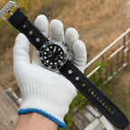 Steeldive SD1987 dive watch on black rubber strap held in gloved hand, wrist scale shot