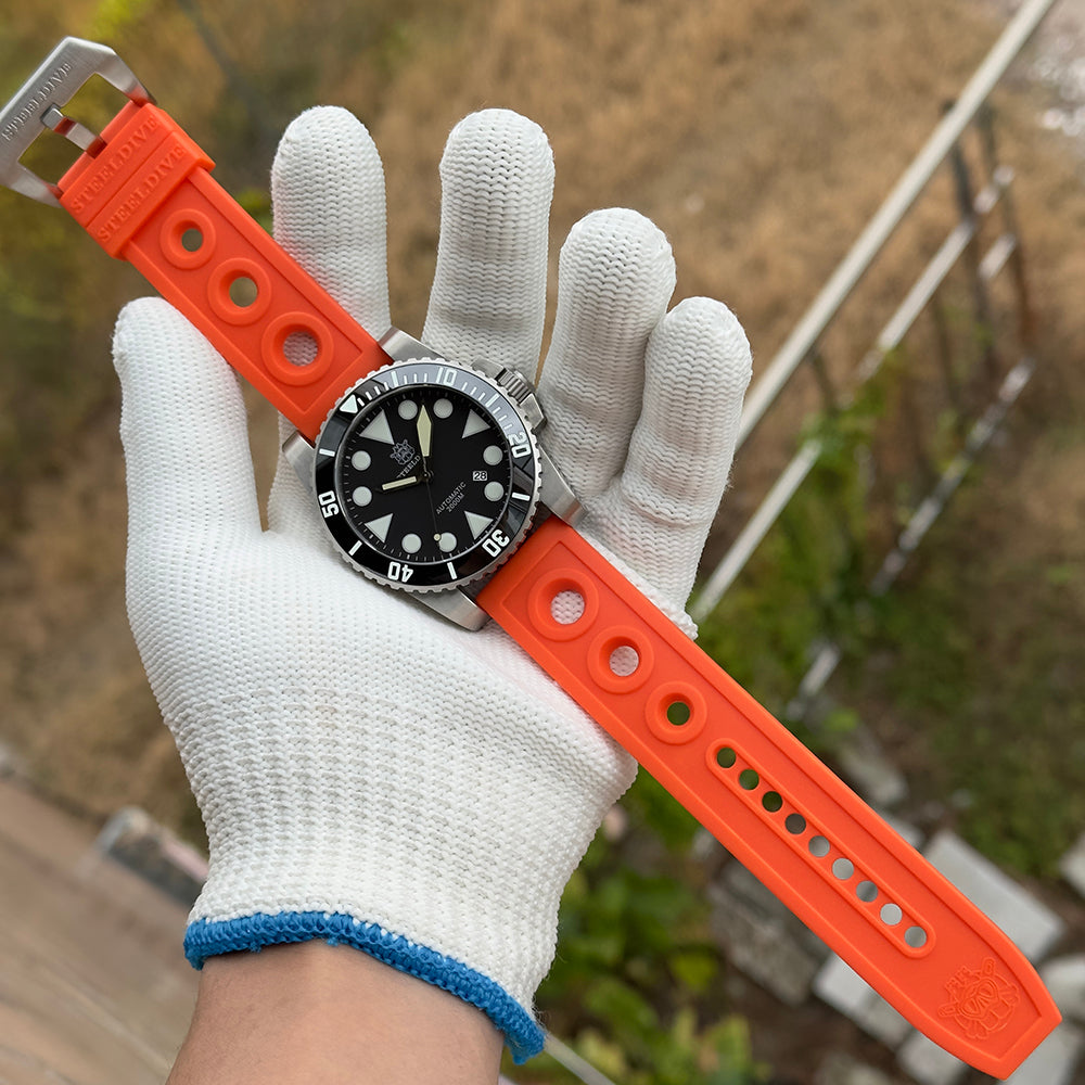 Steeldive SD1987 dive watch on orange rubber strap held in gloved hand outdoors