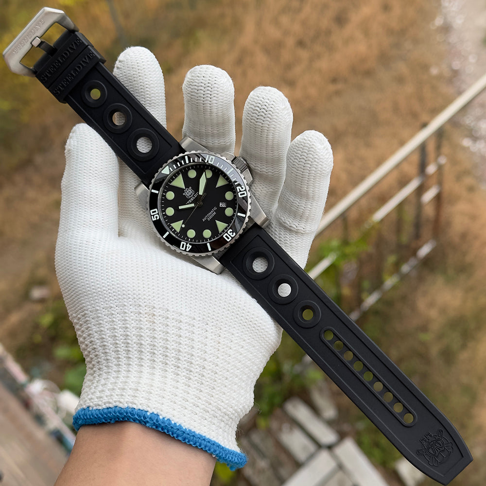 Steeldive SD1987 dive watch with black perforated rubber strap held in gloved hand outdoors, lifestyle
