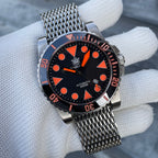 Steeldive SD1987 with orange dial accents on stainless shark-mesh bracelet held in gloved hand