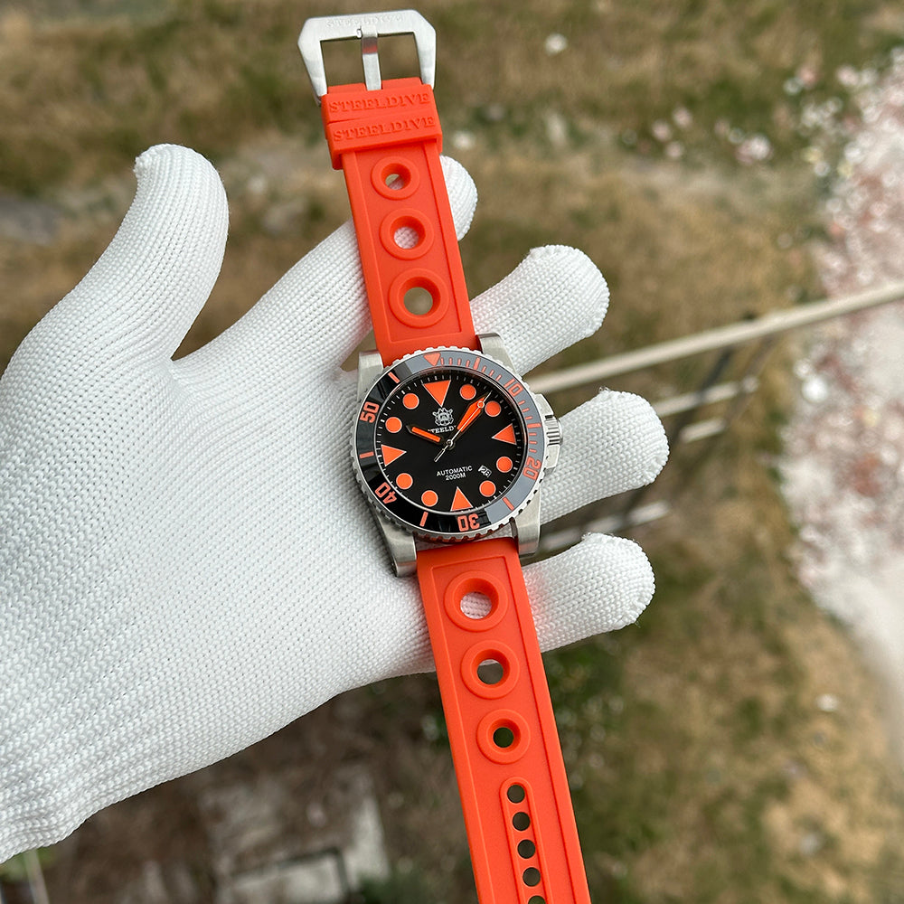 Steeldive SD1987 on orange rubber dive strap lifestyle shot in gloved hand outdoors