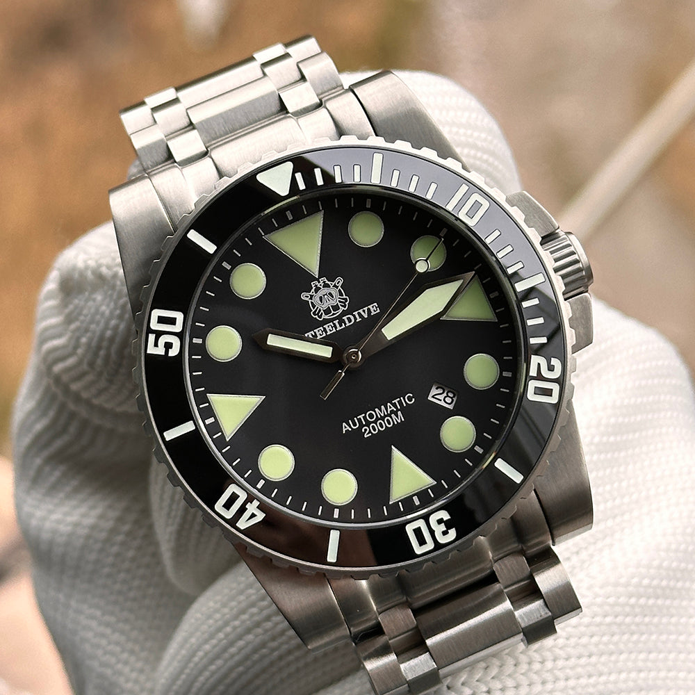 Steeldive SD1987 black dial macro showing green-cream lume indices, Steeldive logo and date window