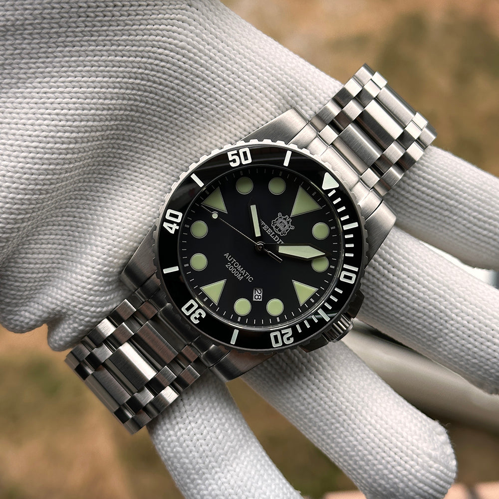 Steeldive SD1987 black dial green-lume variant on tank bracelet held on white glove outdoors