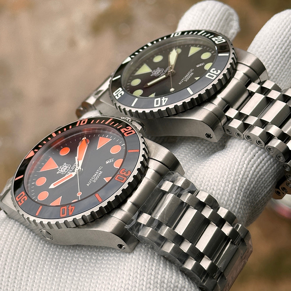 Steeldive SD1987 dial comparison showing orange variant and green-lume black variant on tank bracelet