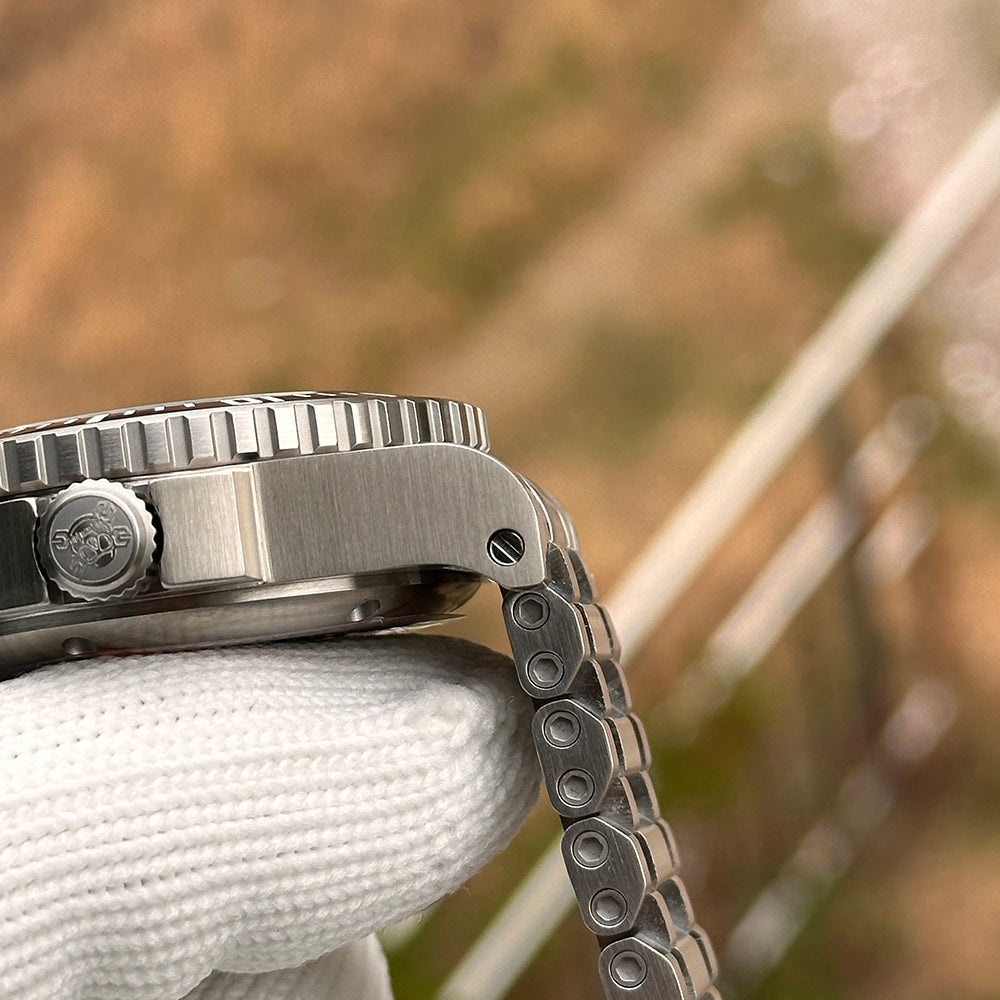 Steeldive SD1987 screw-down crown close-up with SD logo and brushed case flank on tank bracelet