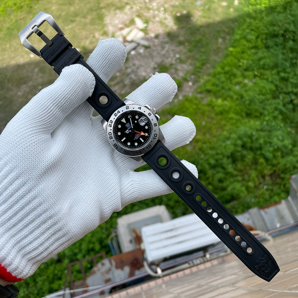 Steeldive SD1992 GMT dive watch with black perforated rubber strap laid across a gloved hand